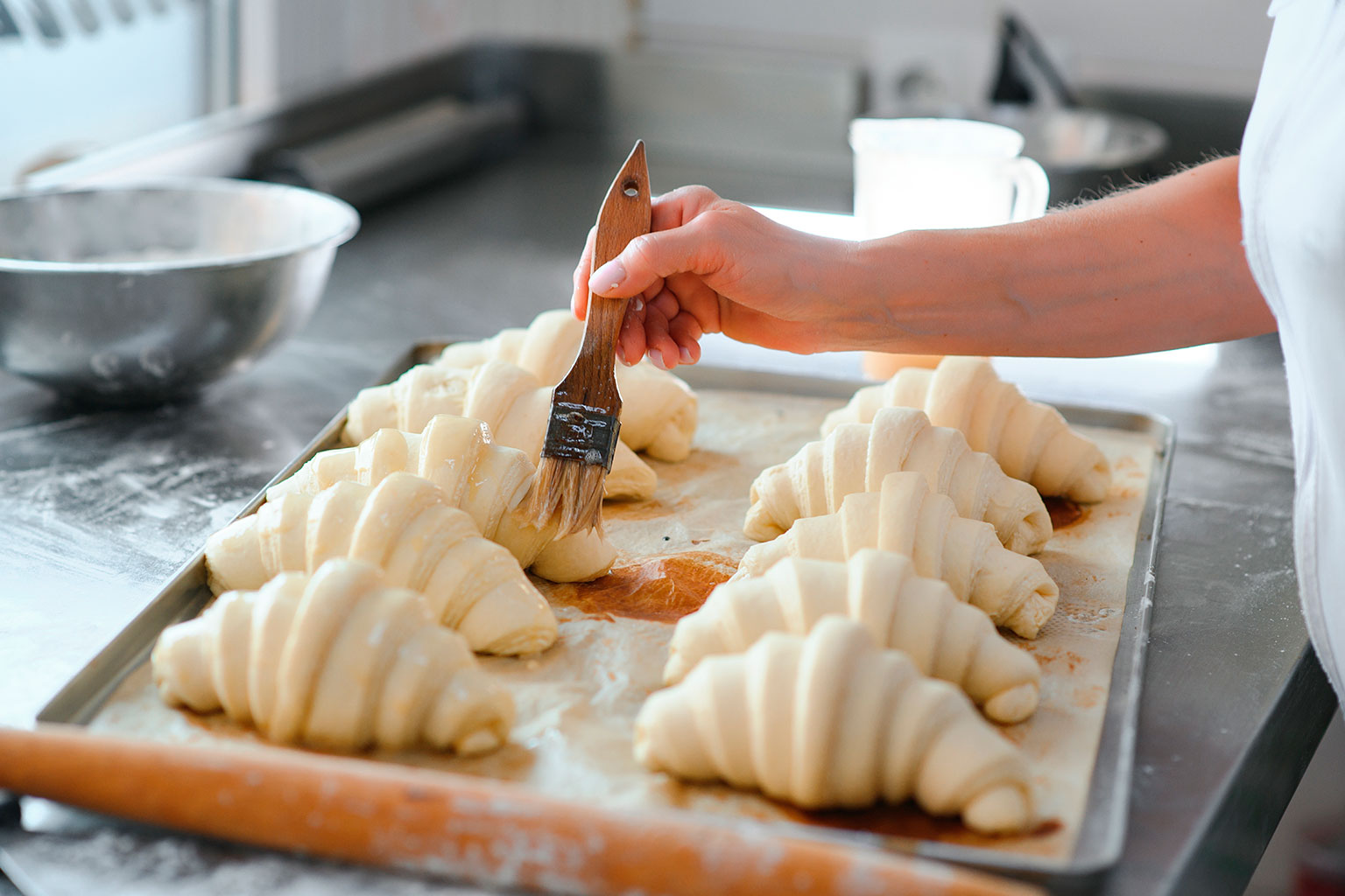 mao-pincelando-ovo-no-croissant-panificacao-confeitaria-margarina-especifica